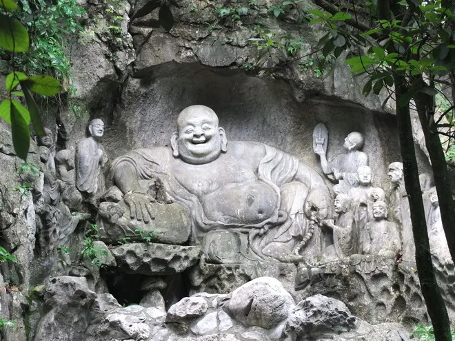 杭州飛來峰石窟的“笑佛”,是現存最早的大肚彌勒形象。造像為席地而坐的樣式,亨手按著布袋,左手持丫串念珠,面呈憨厚笑容,雙耳垂肩,下巴肥厚。本肚凸起,腹下束著一根繩,表情豐富、慈祥。在大肚彌勒兩旁雕塑了十八羅漢像,環侍在彌勒身邊。在彌勒像旁有